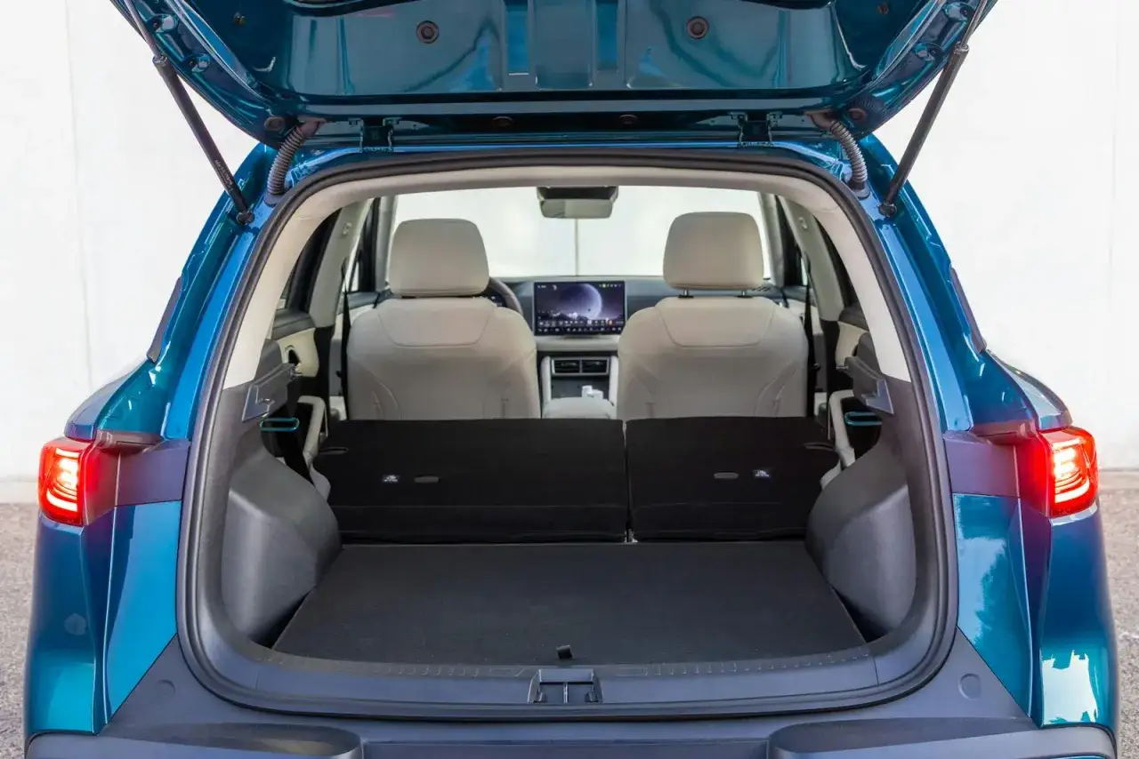 Maletero abierto de coche azul, asientos beige y pantalla t&aacute;ctil. Listo para el atto 2 de tu viaje.