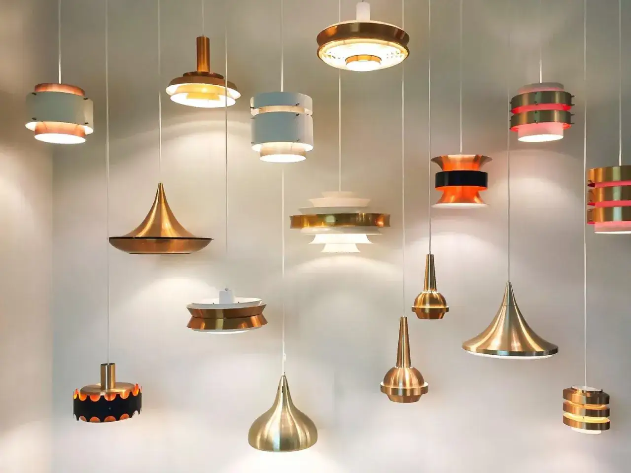 Colección de lámparas colgantes de diseño, algunas de cobre y otras de metal blanco y dorado, creando un ambiente moderno.