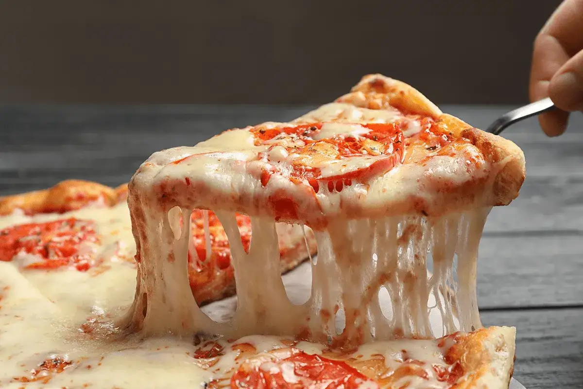 Rozciągający się ser do pizzy z pomidorami, kuszący apetycznym widokiem.