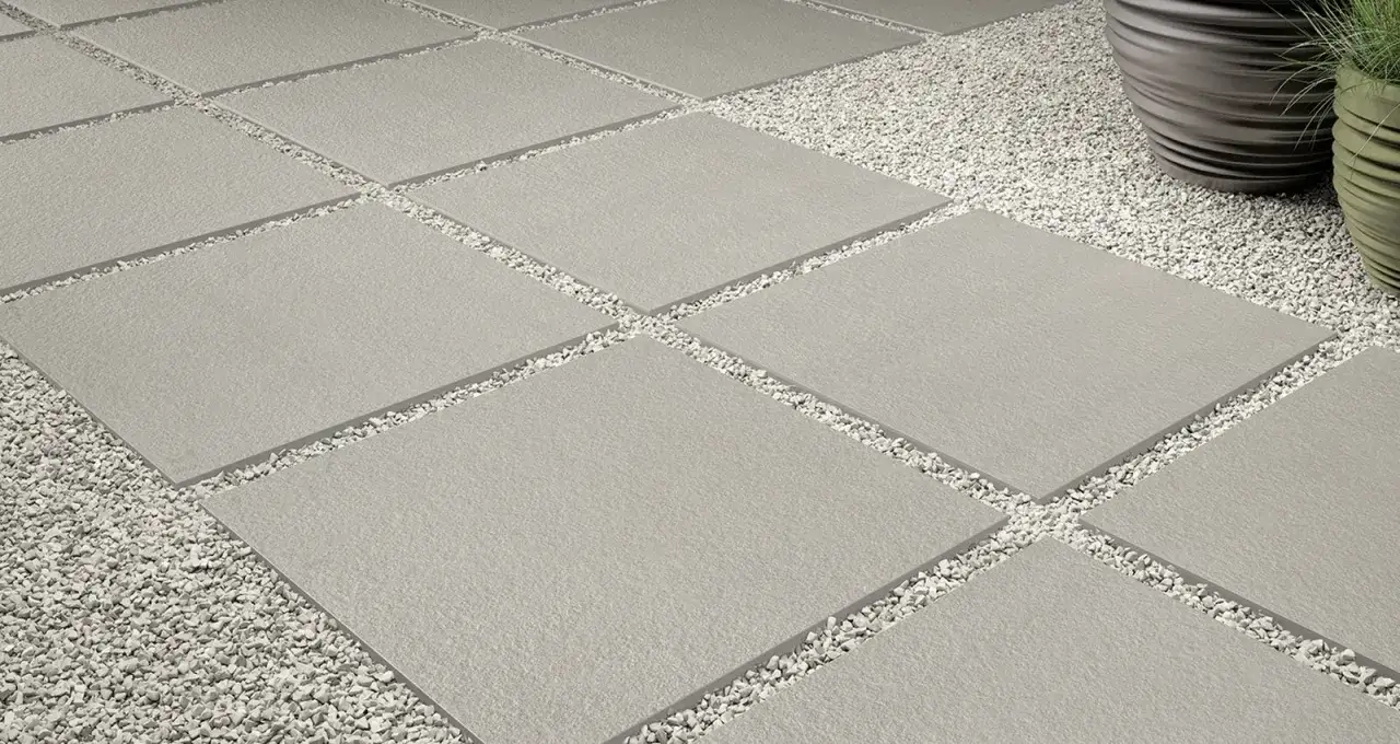 Posa a secco su ghiaia: lastre quadrate grigie alternate a ghiaietto bianco creano un percorso moderno e pulito.