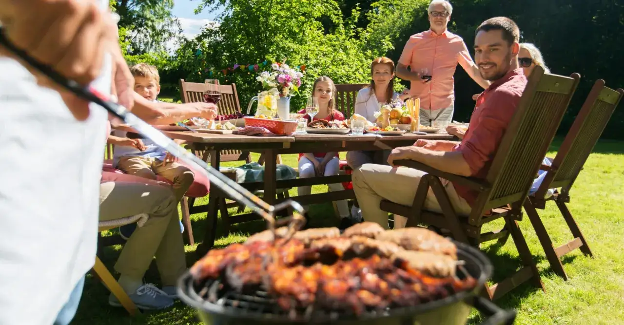 Familie genießt ein Sommerfest im Garten. Auf dem Grill brutzeln Leckereien – so lecker, dass man sich fragt, was kann man grillen!