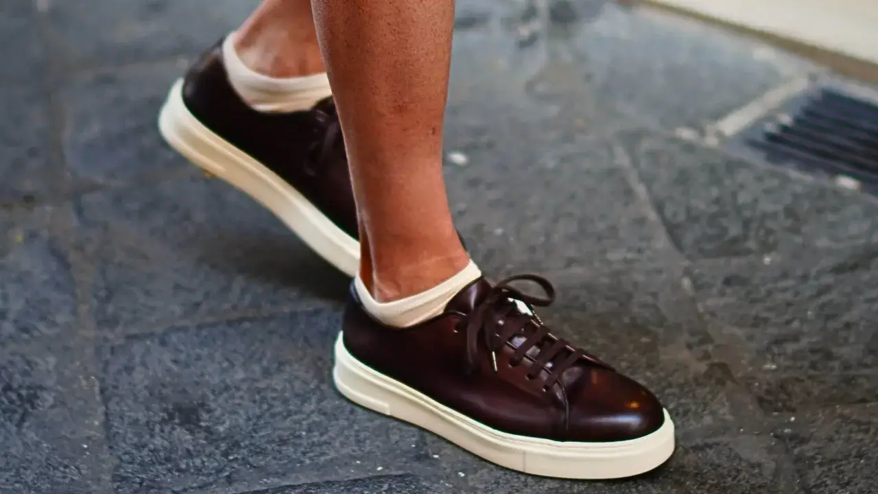 Un uomo indossa sneakers marroni con calze bianche corte. Un look casual e alla moda per scoprire quali calze con sneakers uomo stanno meglio.