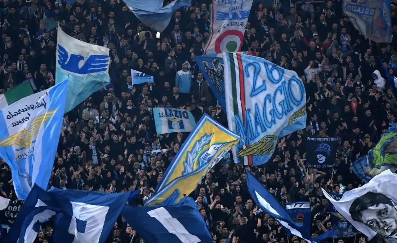 Tłum kibiców włoskiego klubu piłkarskiego Lazio, machający flagami z orłem i napisami 