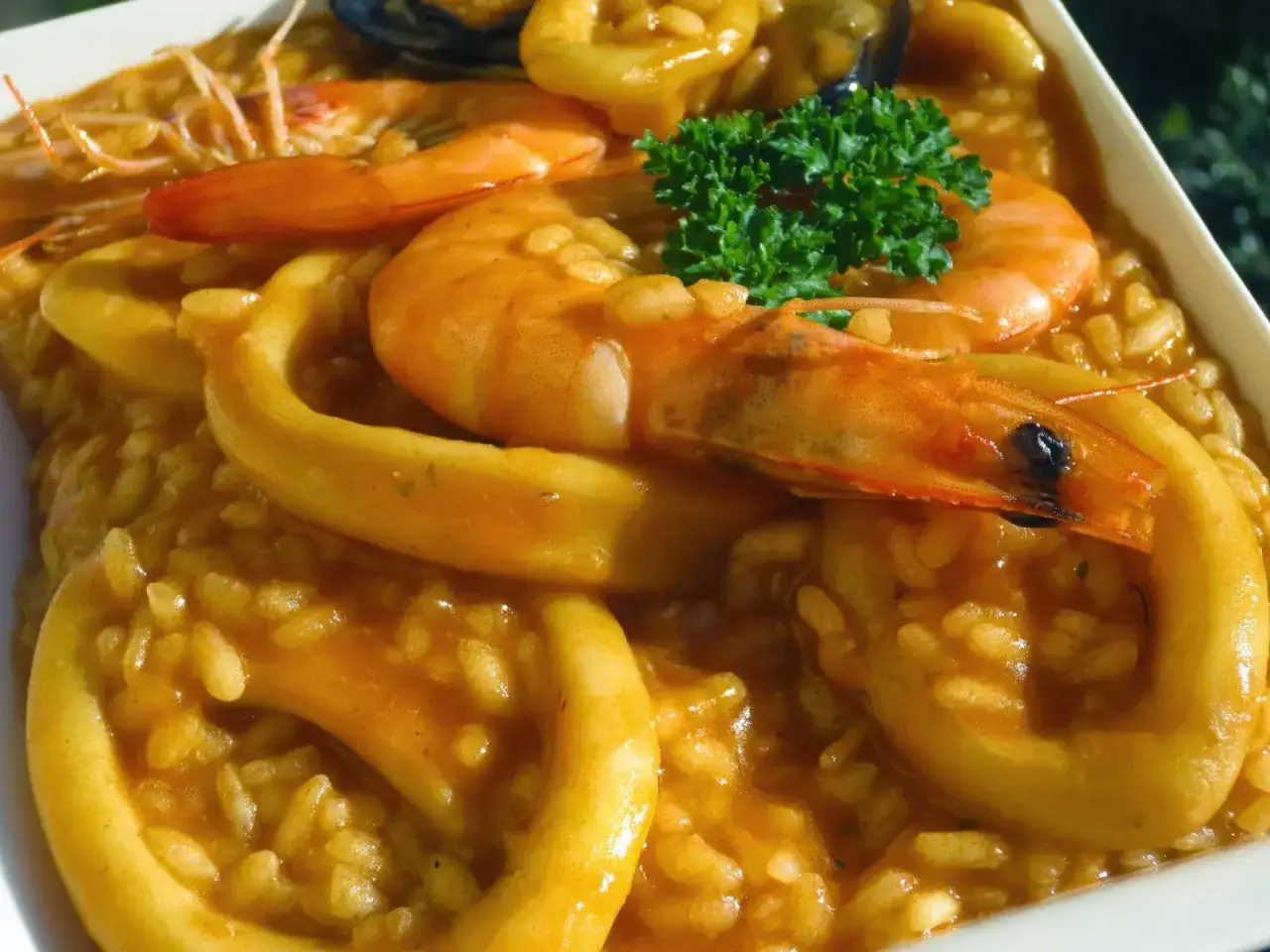 Arroz con calamares y gambas, un plato de mariscos delicioso y colorido, con un toque de perejil fresco.