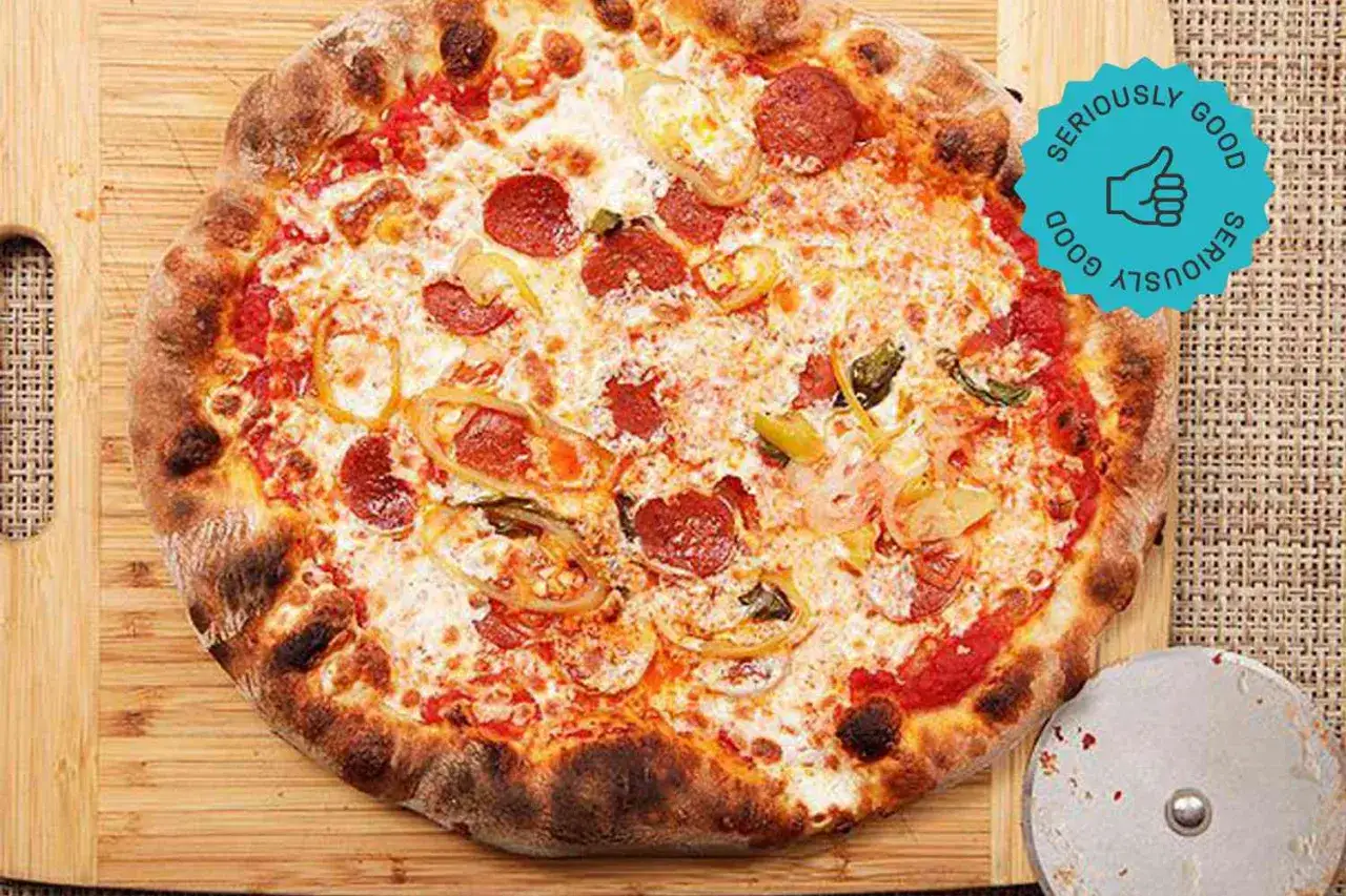 En perfekt napolitansk pizza med pepperoni och grönsaker, redo att skäras.