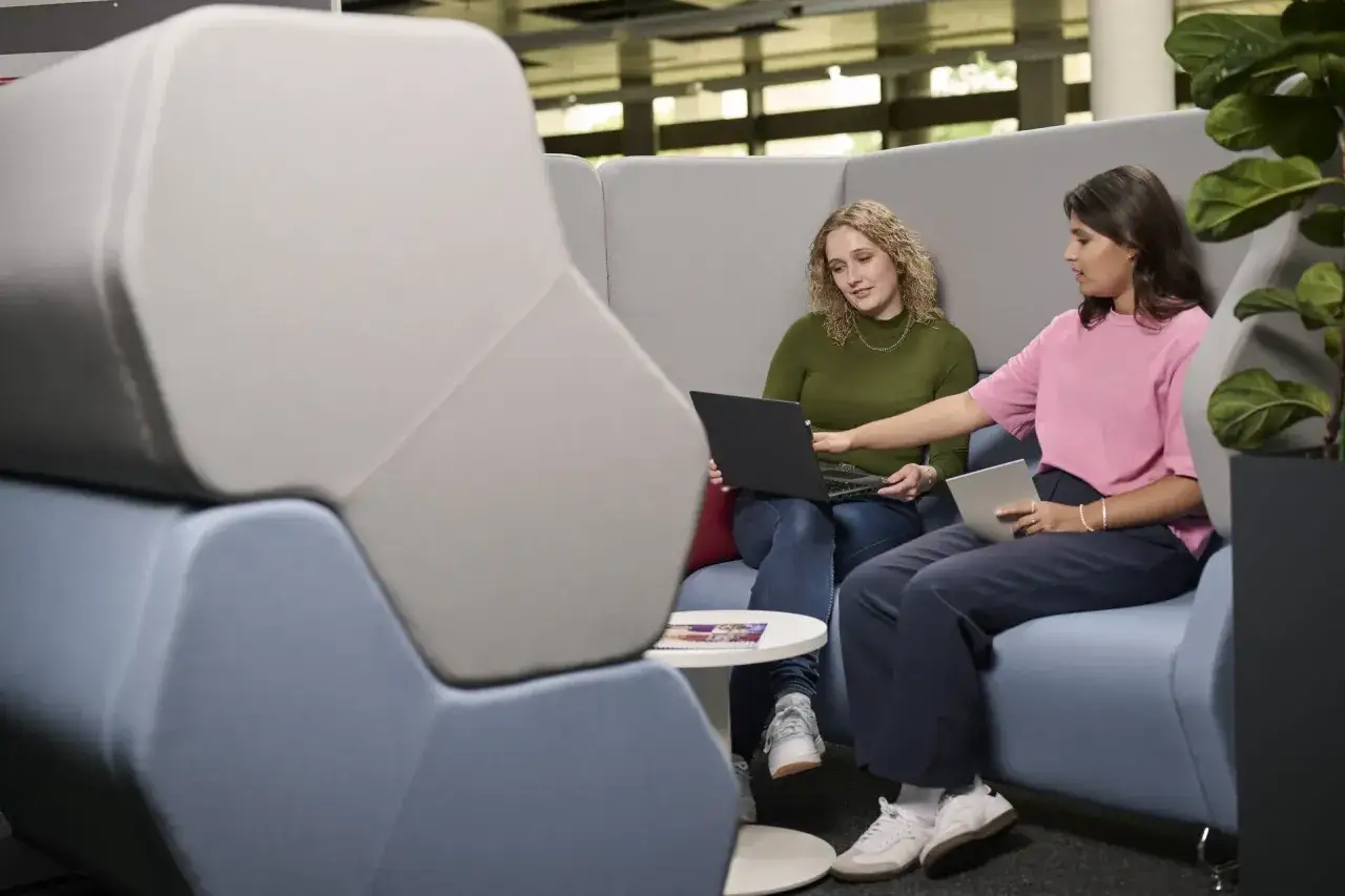 Zwei Frauen besprechen am Laptop eine Präsentation. Sie diskutieren über das Arbeitsmarktmanagement und das Gehalt.