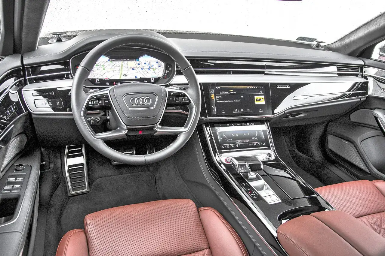 Wnętrze Audi RS8 z brązową skórzaną tapicerką, cyfrowymi zegarami i ekranem multimedialnym.