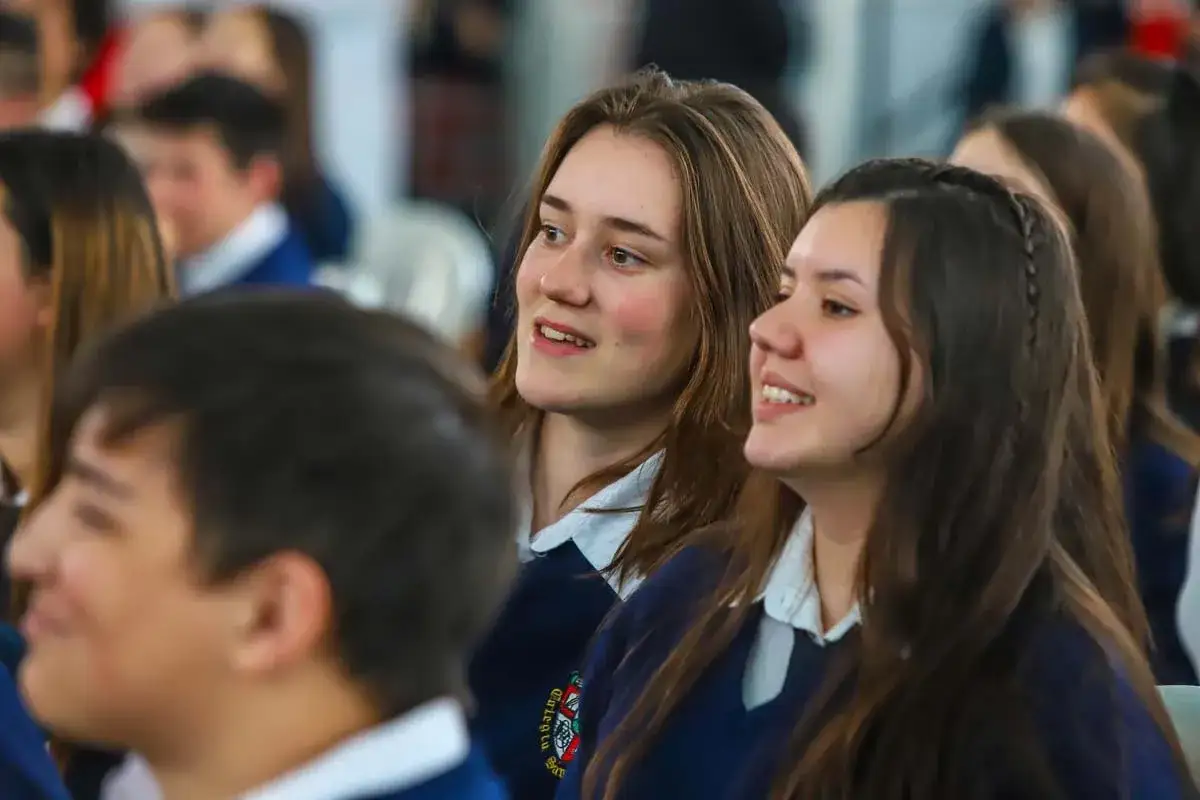 Zwei l&auml;chelnde Sch&uuml;lerinnen im Schuluniform, die gespannt zuh&ouml;ren. Vielleicht ist dies der Beginn ihres Schuljahres im Ausland.