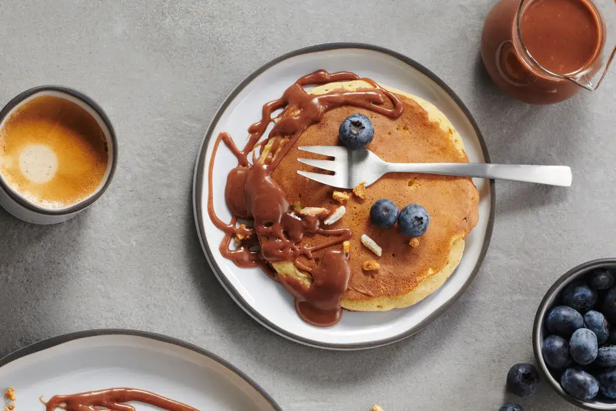 D&eacute;licieux pancakes au chocolat, parfaits pour une recette pancakes p&eacute;pite chocolat. Garnis de myrtilles fra&icirc;ches et d'une sauce au chocolat onctueuse.