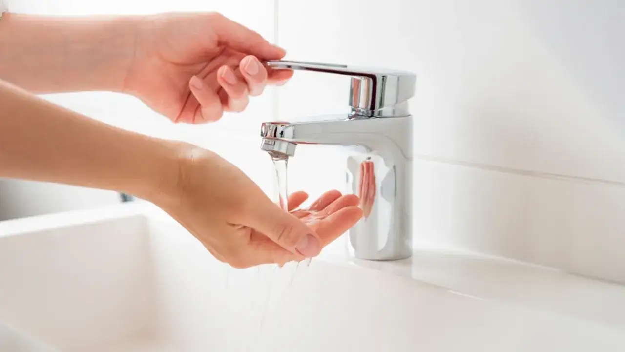 Manos bajo un grifo moderno, el agua fluye con buena presi&oacute;n, ideal para la higiene en casa.