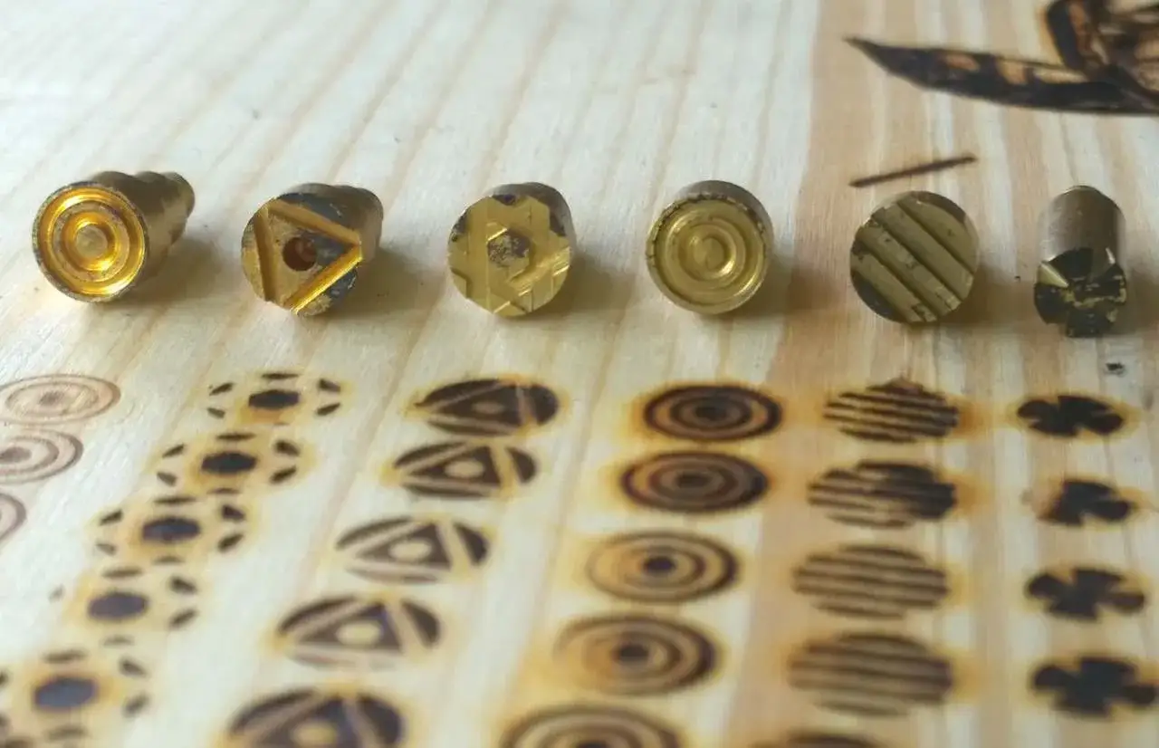 Diverse punte per pirografo con forme geometriche e a cerchio, pronte per creare decorazioni su legno.