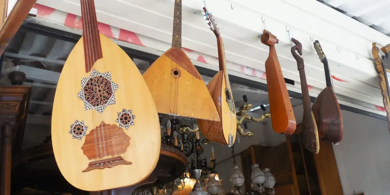 Rząd instrumentów strunowych, w tym grecki instrument muzyczny o nazwie laouto, wisi na haczykach.