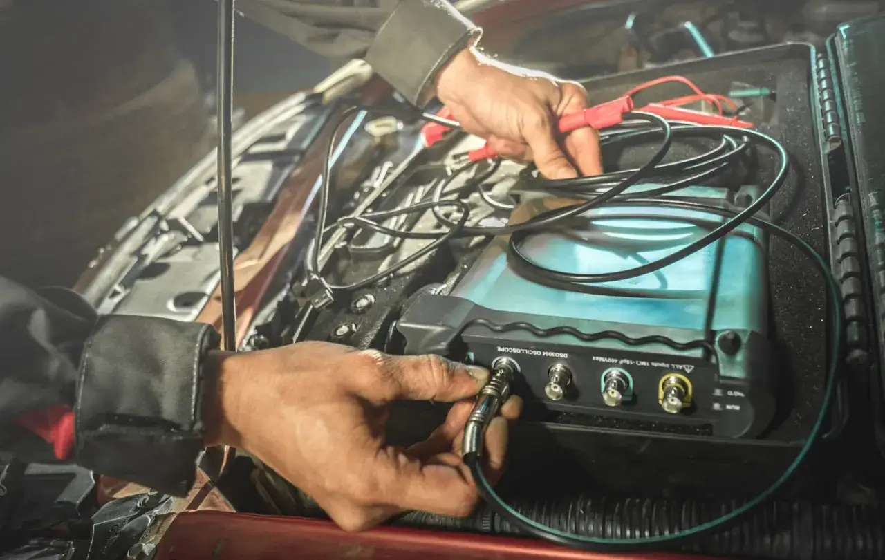 Mechanik podłącza oscyloskop do auta, zastanawiając się, dlaczego mechanicy odmawiają naprawy aut elektrycznych w 2026 roku.