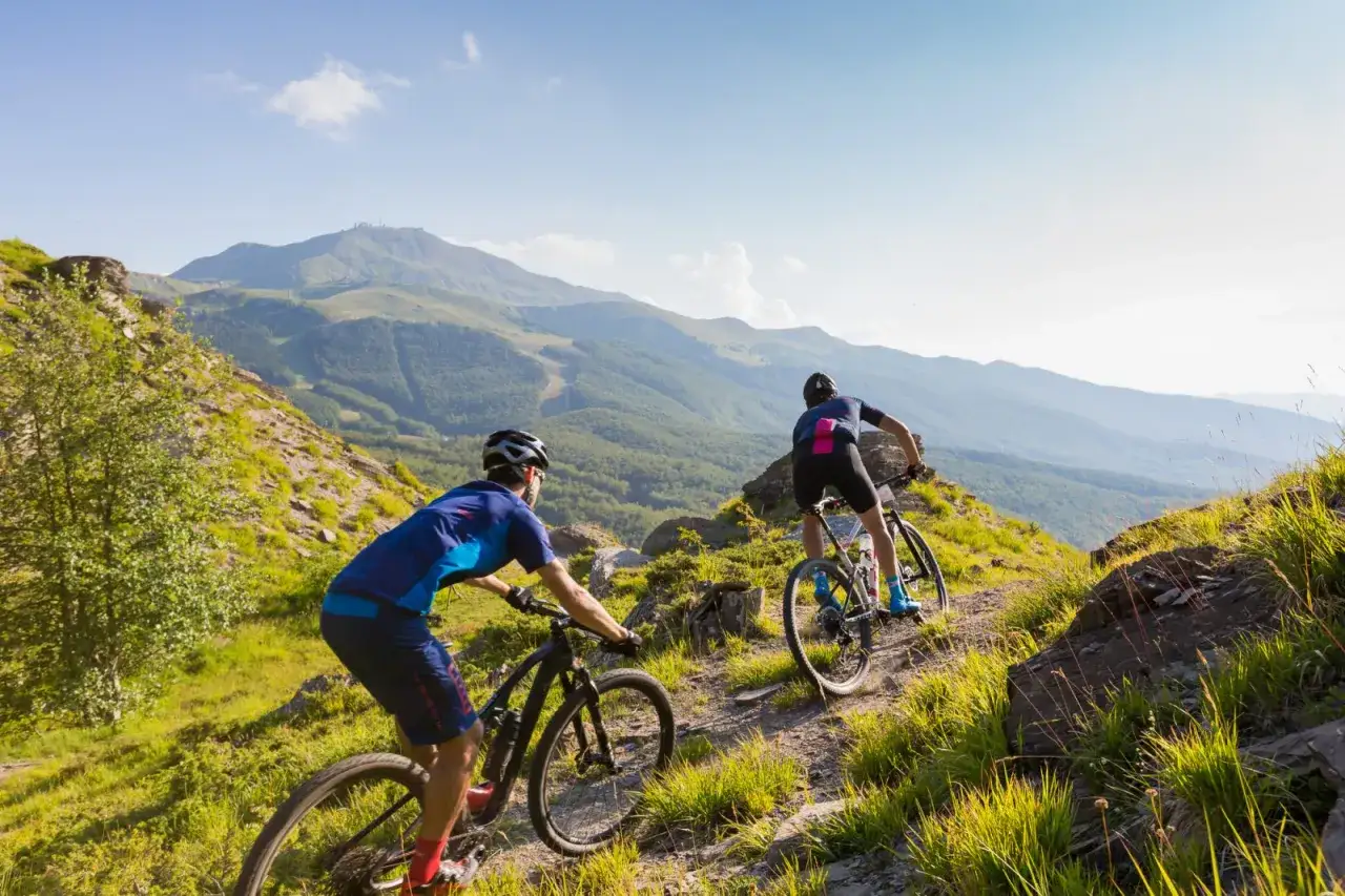 Due ciclisti affrontano un sentiero roccioso in montagna, godendosi un'avventura in bici sulla Via degli Dei.