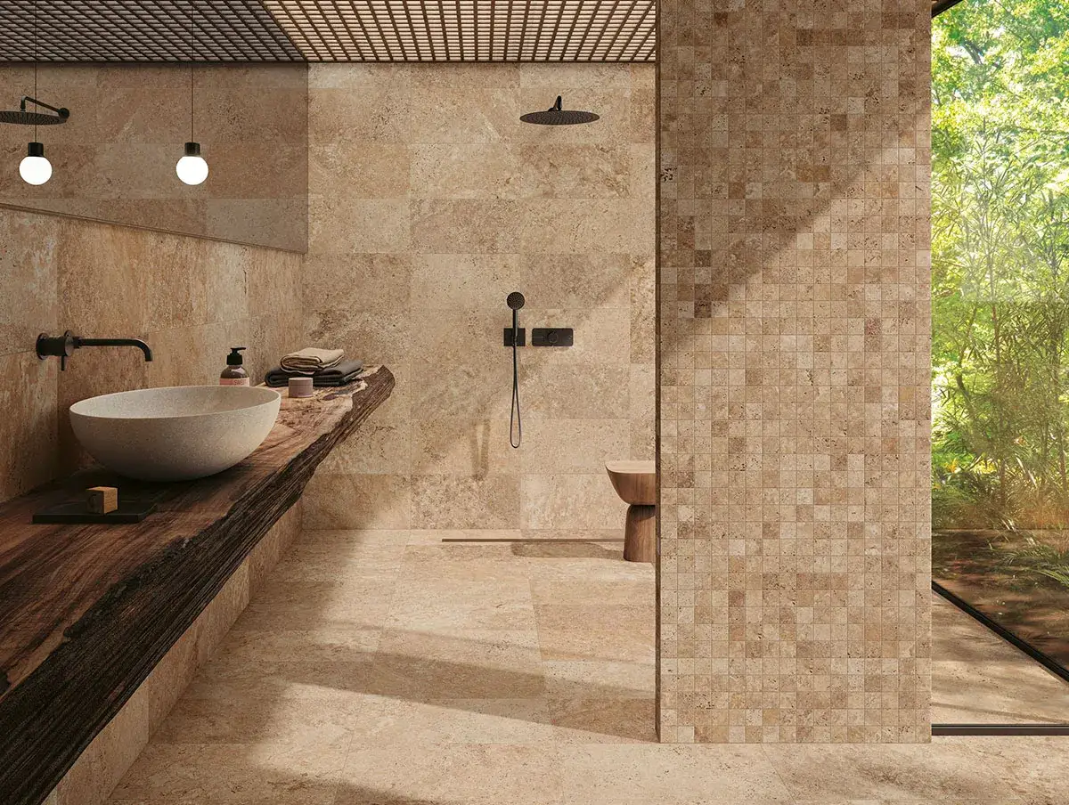 Salle de bain terracotta et beige avec un lavabo en pierre sur un plan de travail en bois brut, une douche &agrave; l'italienne et une grande fen&ecirc;tre donnant sur la verdure.