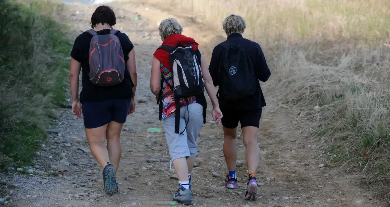 Trois randonneuses profitent d'une marche afghane sur un sentier rocailleux, sac &agrave; dos sur les &eacute;paules, entour&eacute;es par la nature.