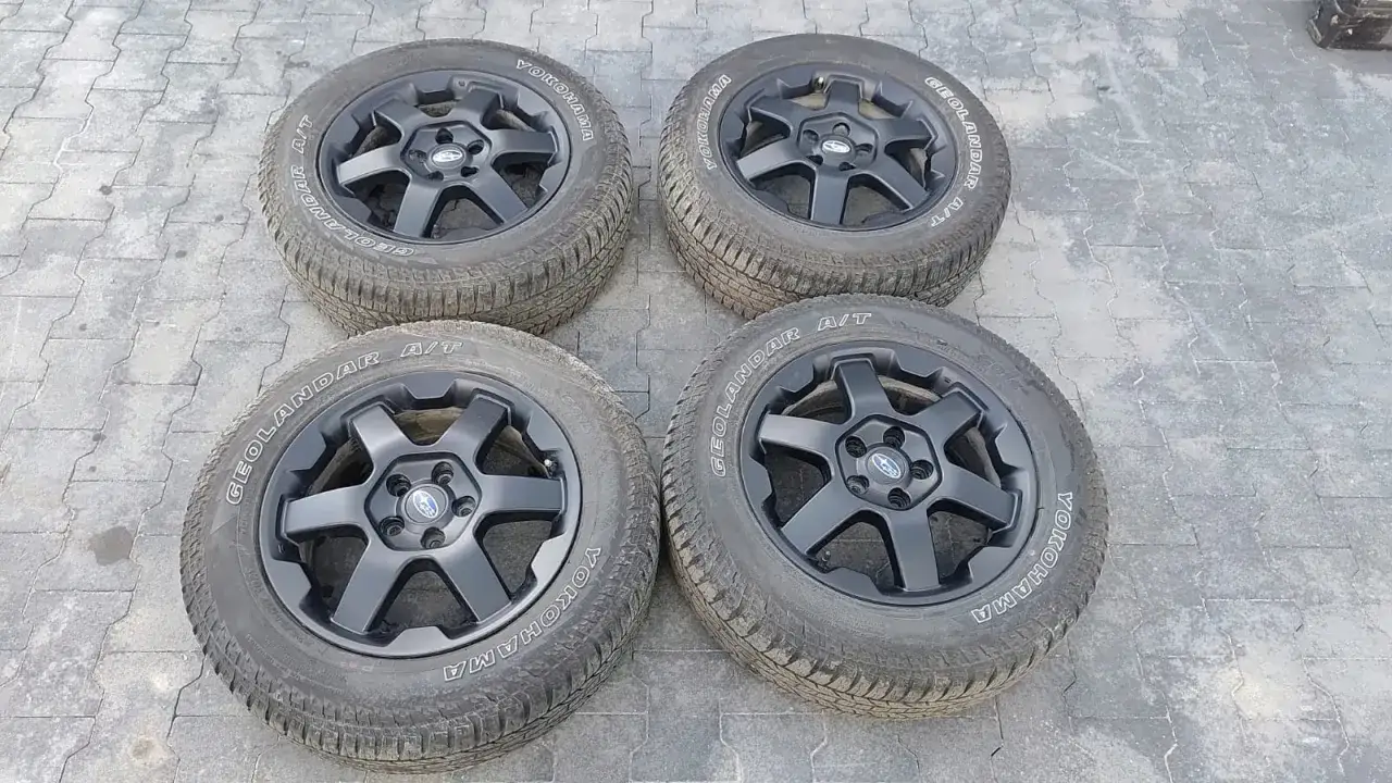 Cztery czarne felgi z oponami Yokohama Geolandar A/T, idealne do Subaru Outback Wilderness, gotowe na przygody.
