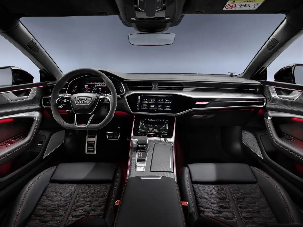 Wnętrze Audi RS 7: czarna skóra z czerwonymi przeszyciami, sportowa kierownica, cyfrowe zegary i ekran multimedialny.