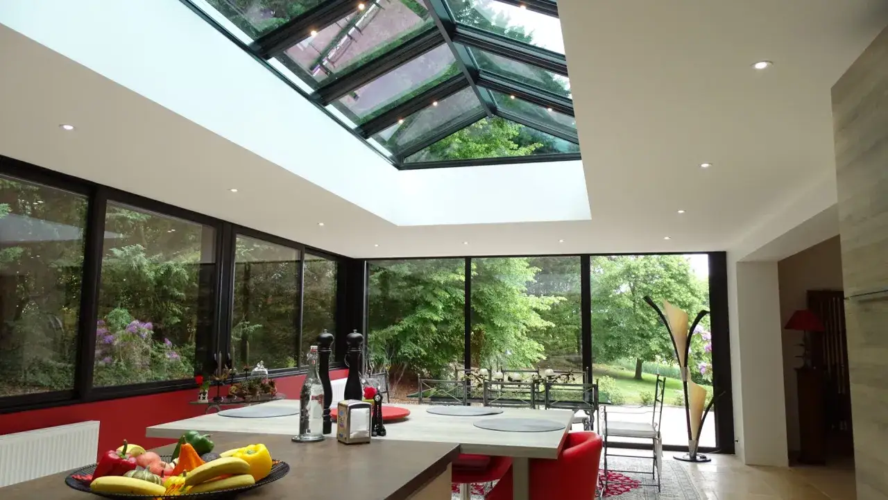 Int&eacute;rieur lumineux avec une cuisine moderne et une **veranda triple vitrage** offrant une vue imprenable sur un jardin luxuriant.