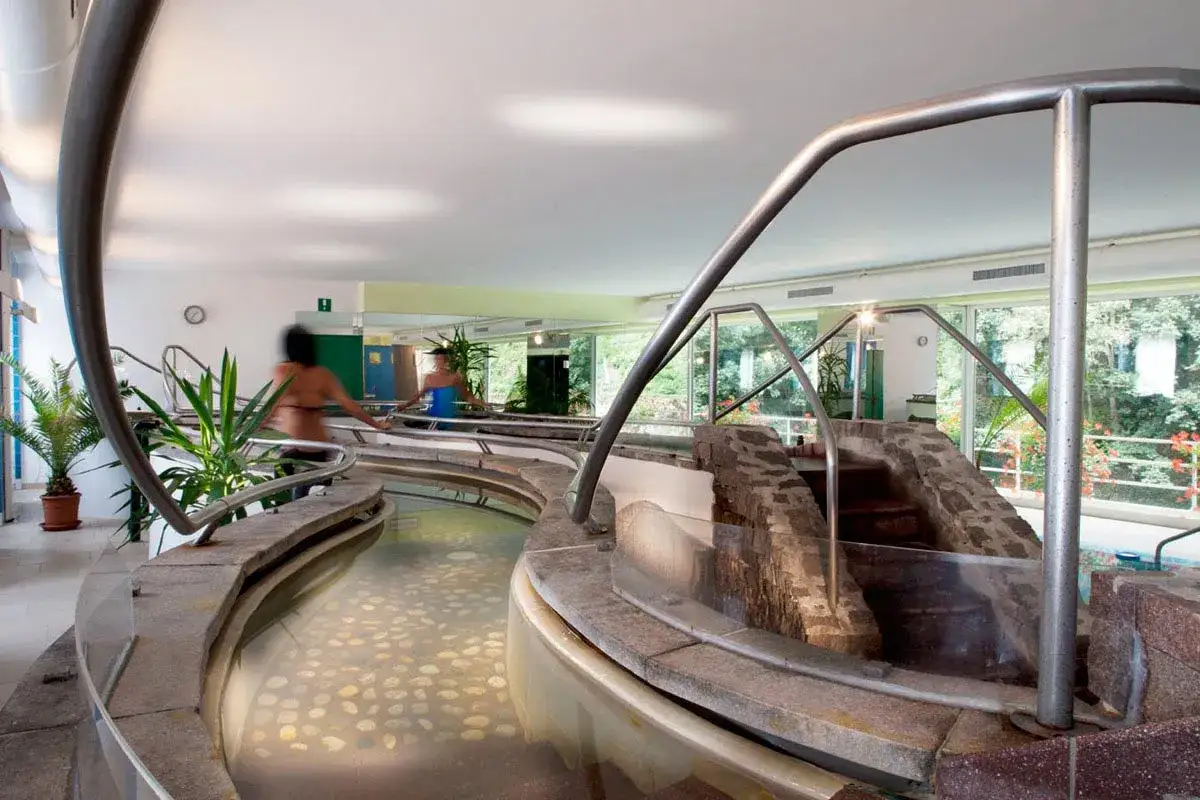 Piscine termali con rocce e piante, persone che si rilassano nei bagni di Rabbi.