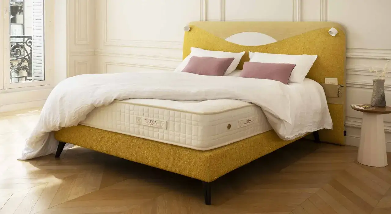 Un lit jaune moutarde avec un matelas Treca. Un surmatelas peut améliorer le confort et la durée de vie de votre matelas.