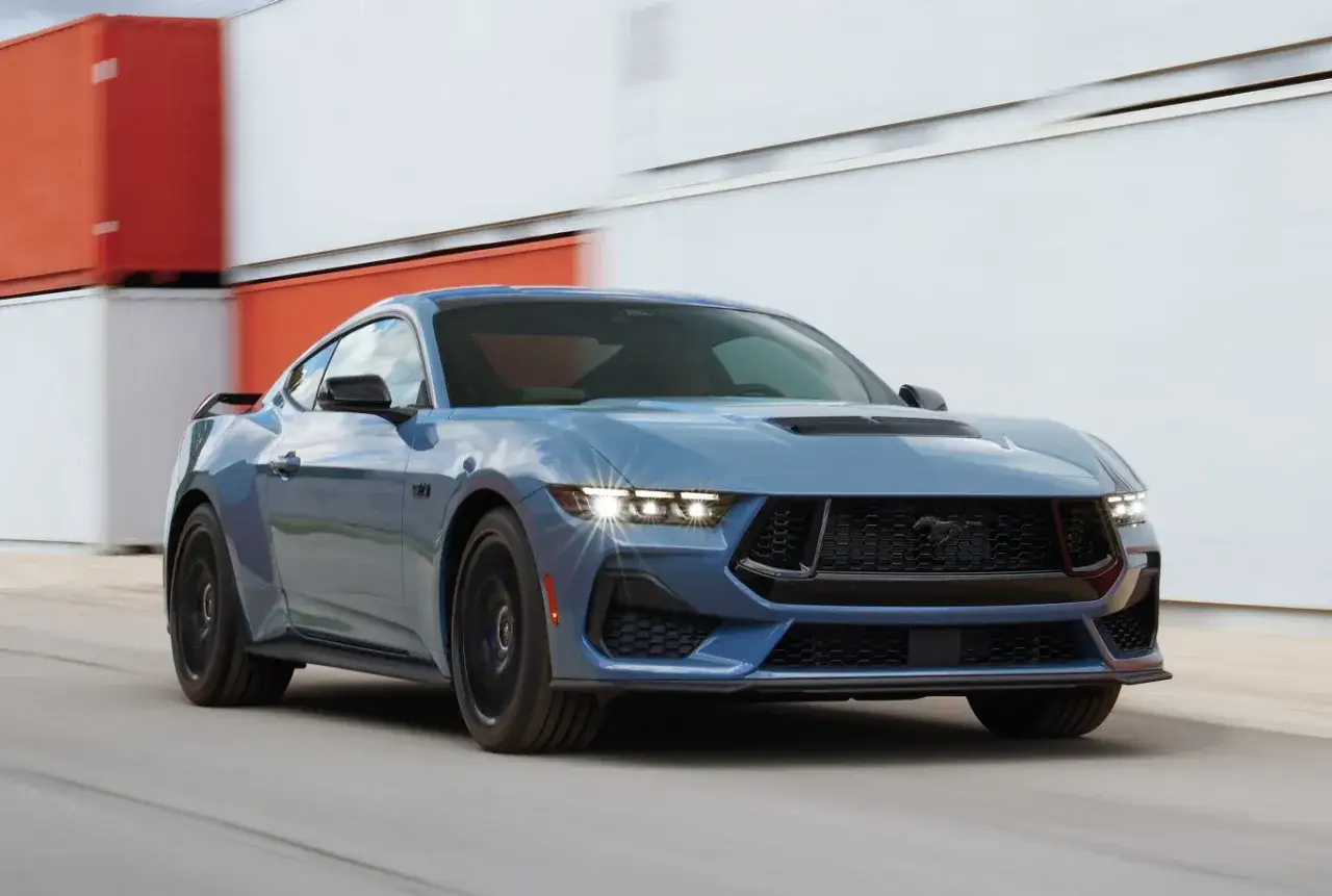 Niebieski Ford Mustang GT w ruchu, z grillem i reflektorami LED. Sprawdź aktualną ford mustang cena.