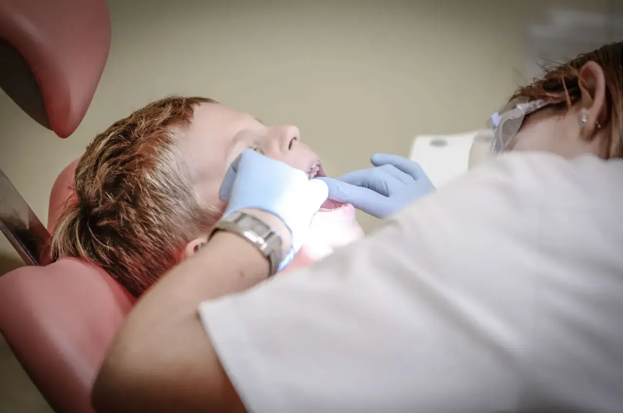 Chłopiec u ortodonty dziecięcego. Dentysta w rękawiczkach bada zęby dziecka.
