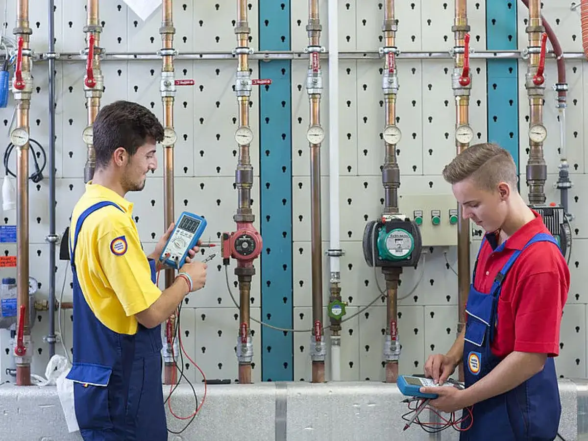 Zwei Auszubildende pr&uuml;fen mit Messger&auml;ten eine Heizungsanlage. Ein guter anlagenmechaniker gehalt netto ist erstrebenswert.