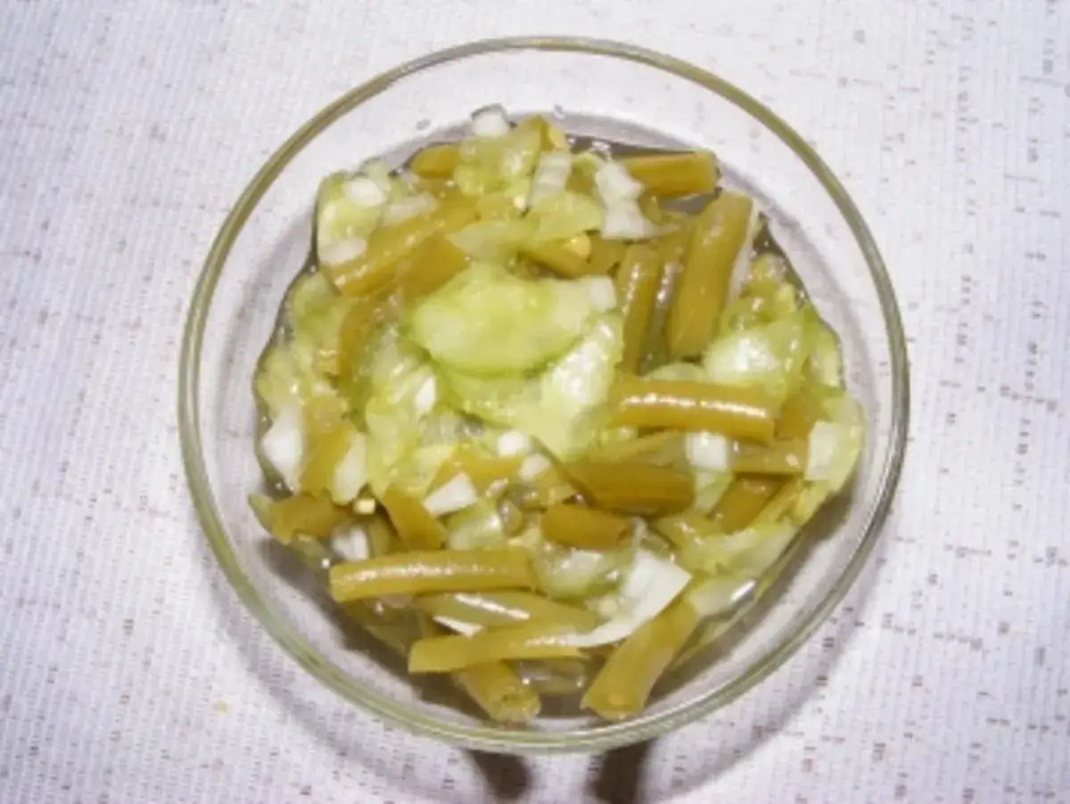 Frischer Bohnen Gurken Salat in einer Glasschüssel, mit Zwiebeln und einer leichten Vinaigrette.