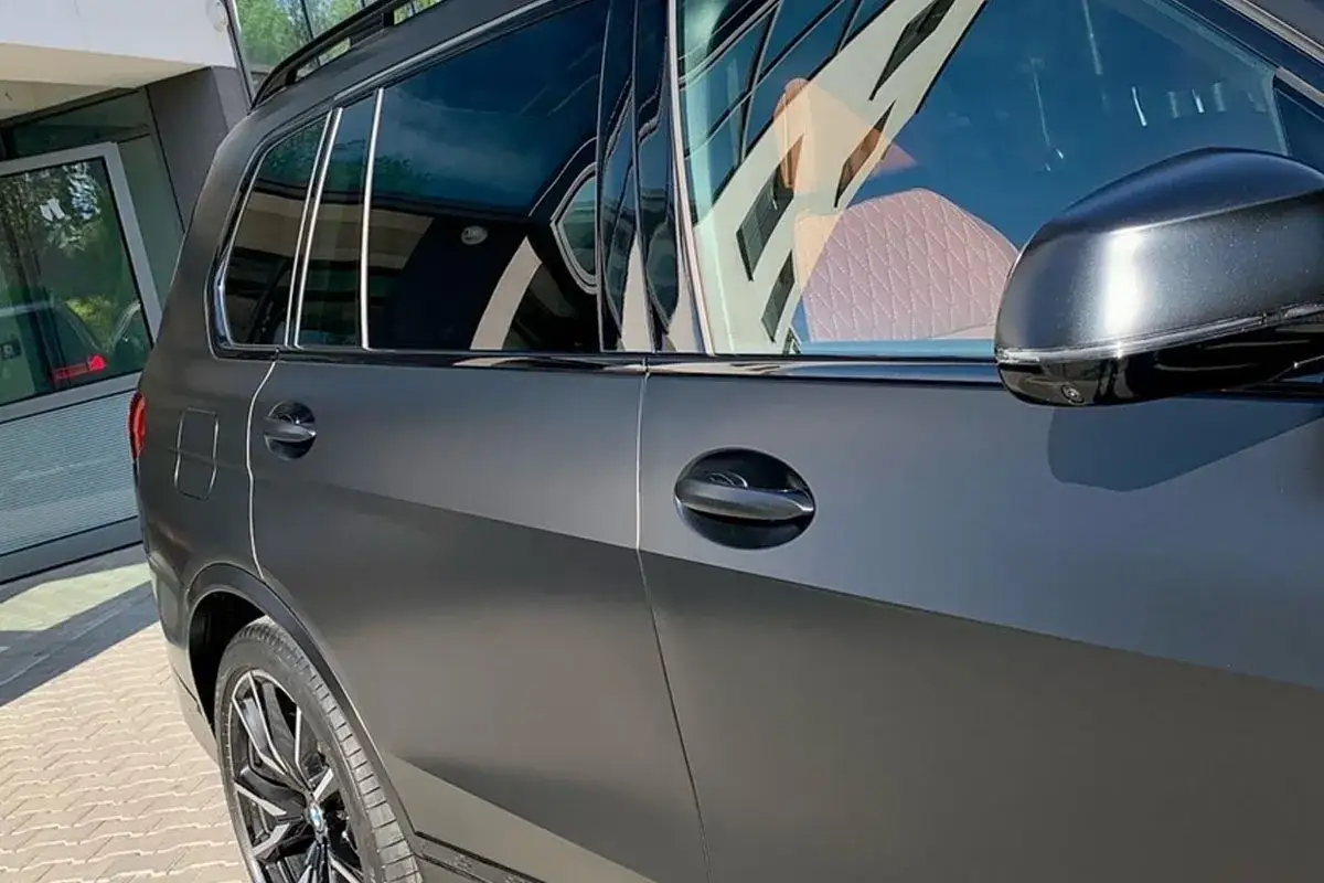 Matowy, ciemnoszary SUV z beżową, pikowaną tapicerką widoczną przez okno. Lśniące detale i felgi podkreślają jego elegancję. Idealny wybór dla miłośników stylu i ochrony PPF.