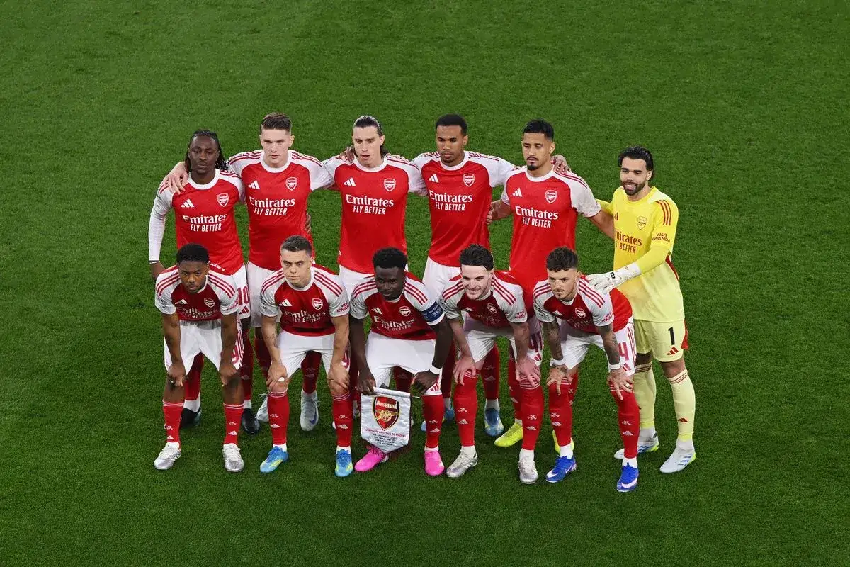 Arsenal F.C. &ndash; zawodnicy w czerwonych strojach pozują do zdjęcia na zielonej murawie. Jeden z nich trzyma transparent z logo klubu.