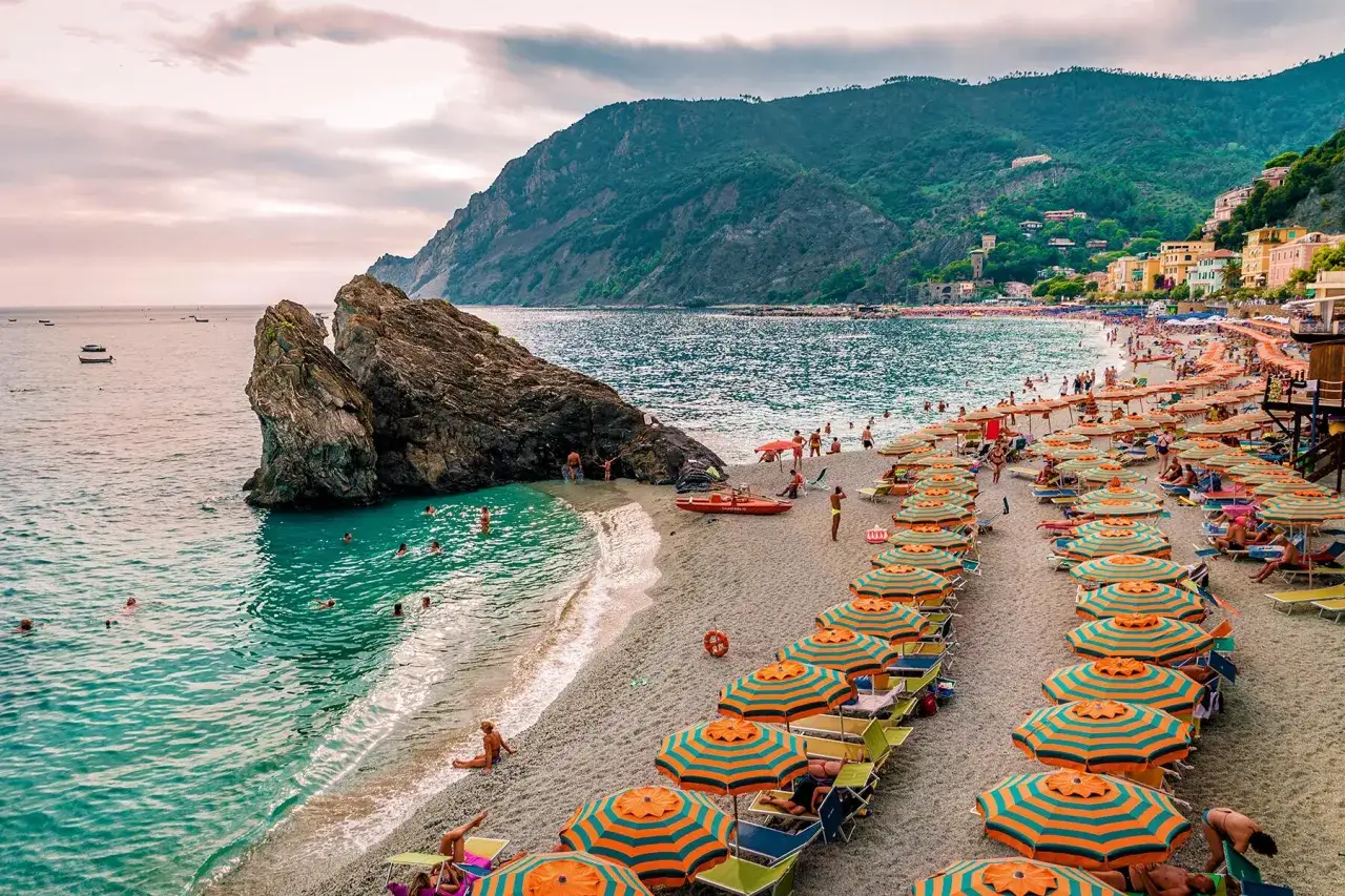 Słoneczna plaża z rzędami parasoli i turkusową wodą, jedna z najpiękniejszych plaż we Włoszech.