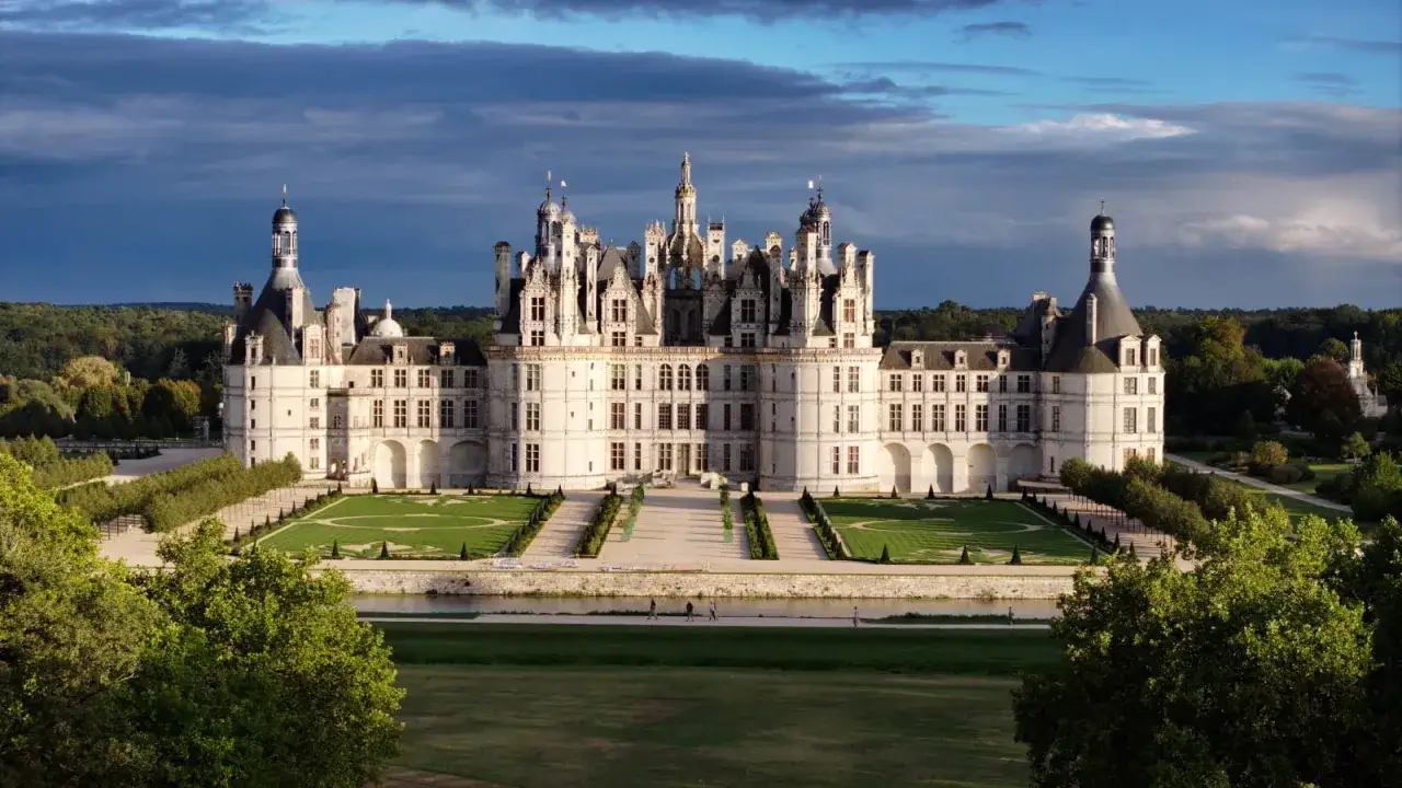 Le majestueux **Château de Chambord** se dresse, baigné par une lumière douce, avec ses tours et son architecture Renaissance impressionnante.