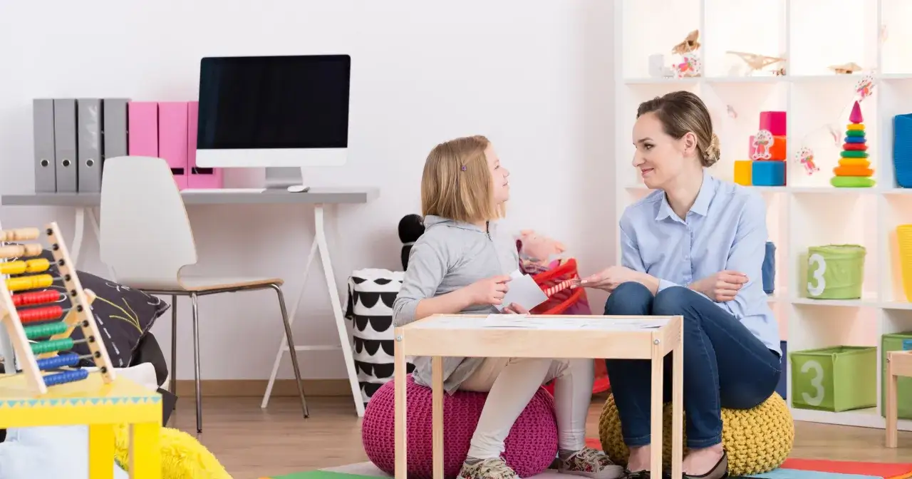 Terapeutka pracuje z dziewczynką nad komunikacją, wspierając ją w walce z afazją u dzieci.