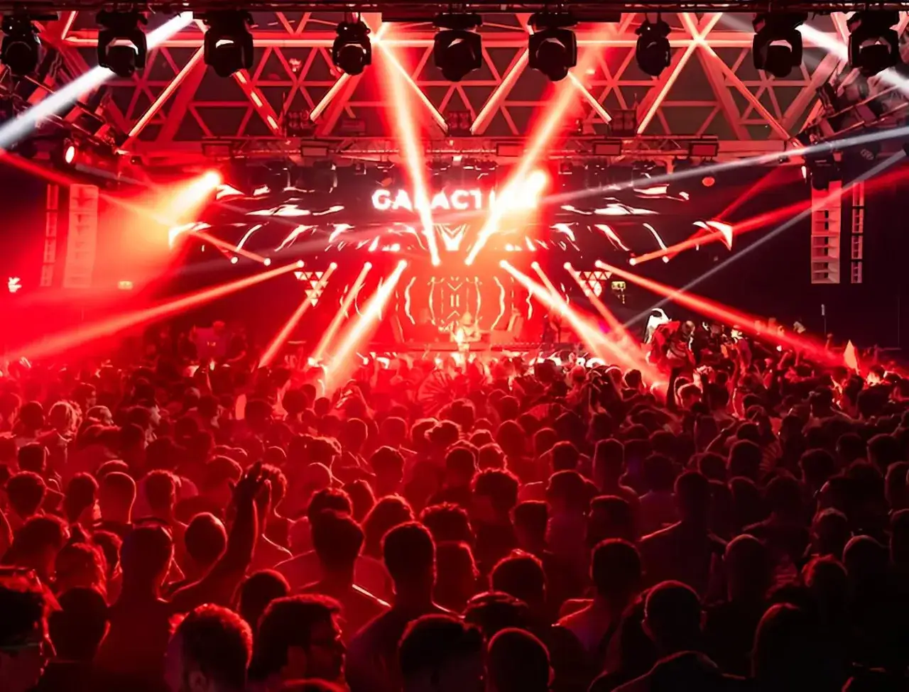 Folla in delirio sotto un tripudio di luci rosse, mentre sul palco risuonano le canzoni techno del momento.