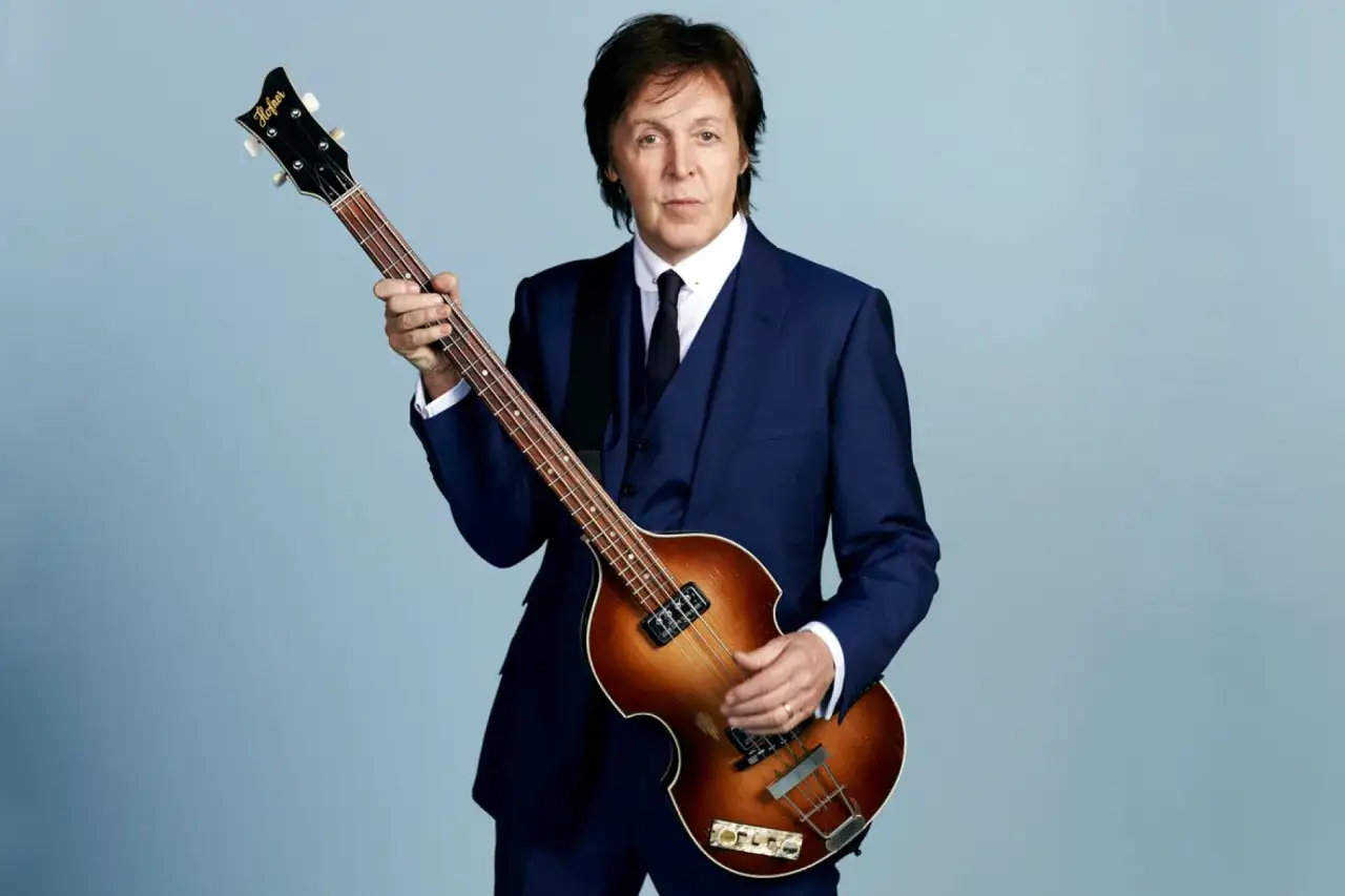 Paul McCartney, legendarny basista The Beatles, w eleganckim garniturze trzyma swoją kultową gitarę Höfner.