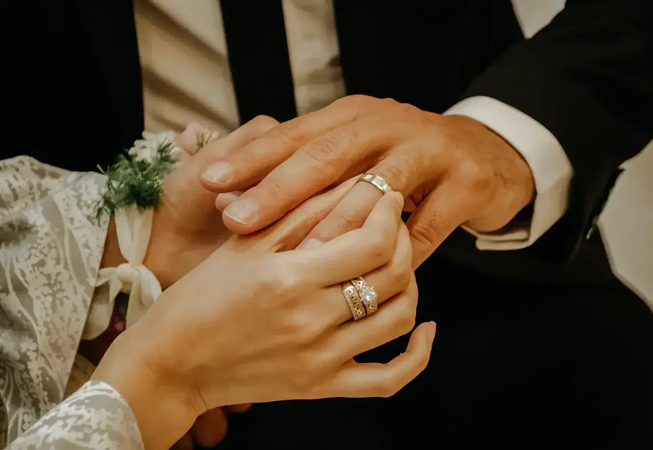 Ein Händchen hält einen Ring, um ihn am Finger des Partners zu befestigen. Ein Symbol für die ehe bedeutung.