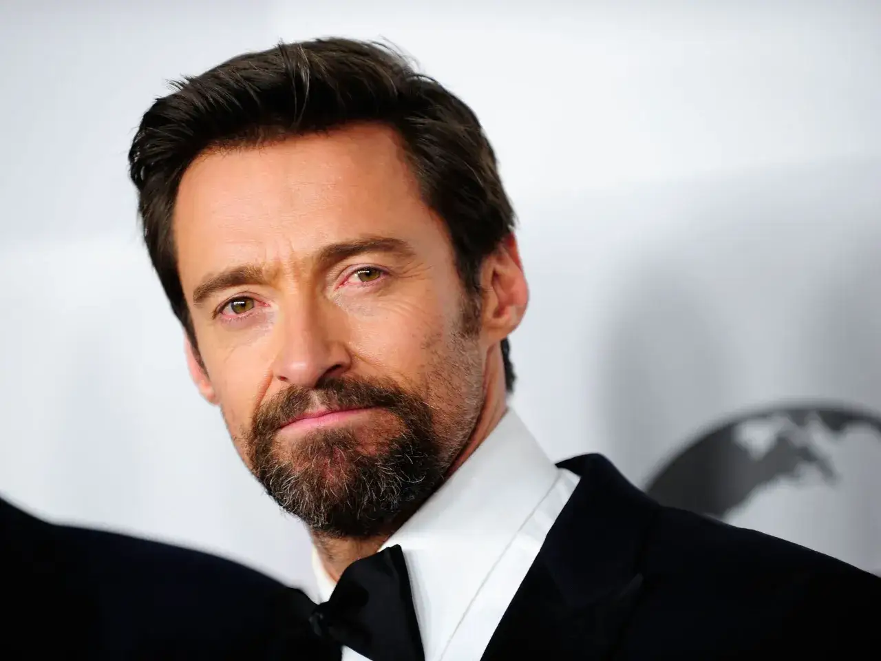 Hombre con barba van dyke, traje oscuro y pajarita negra.