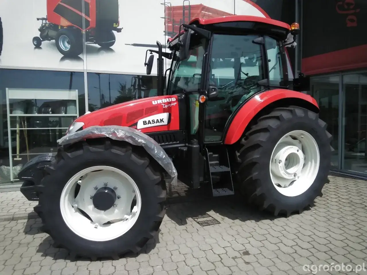 Czerwony traktor URSUS BASAK, gotowy do pracy na polu. Marzenie o własnym, sprawnym ciągniku i prawo jazdy na ciągnik staje się rzeczywistością.