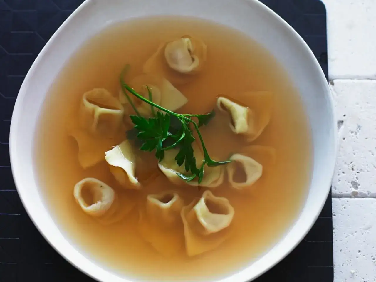 Eine Sch&uuml;ssel mit herzhaftem Tortellini in Brodo, garniert mit frischer Petersilie.