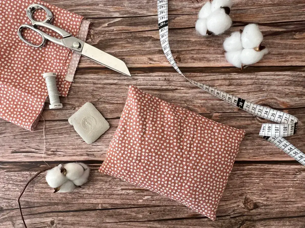 Matériel pour faire une bouillotte maison : tissu à cœurs, ciseaux, fil, craie, coton et mètre ruban.