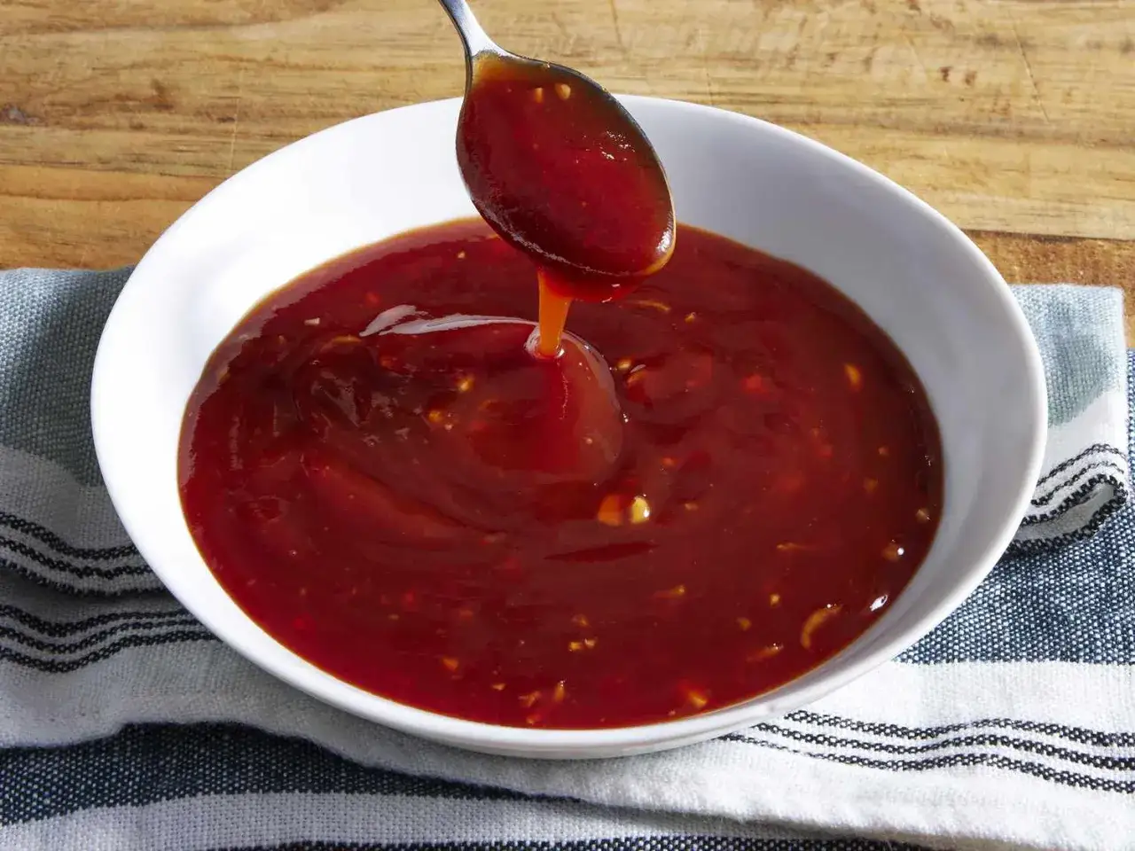 Łyżka polewa miskę gęstym, aromatycznym sosem tonkatsu. Idealny dodatek do dań.