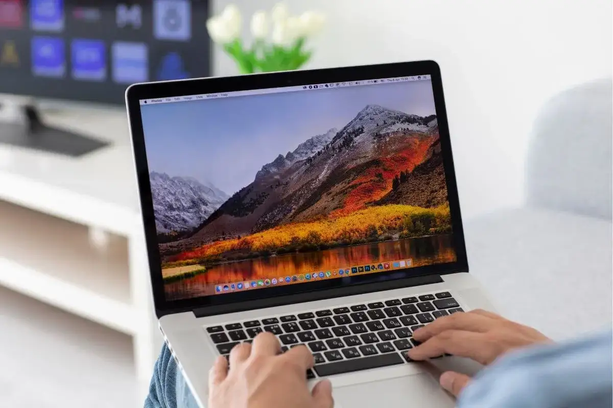 Osoba pisze na laptopie z pięknym widokiem gór. Chcesz wiedzieć, jak zrobić screena na laptopie?