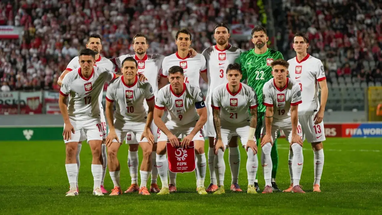 Piłkarze reprezentacji Polski w białych strojach, gotowi do gry. To efekt powołań do kadry, która prezentuje się dumnie na tle kibiców.