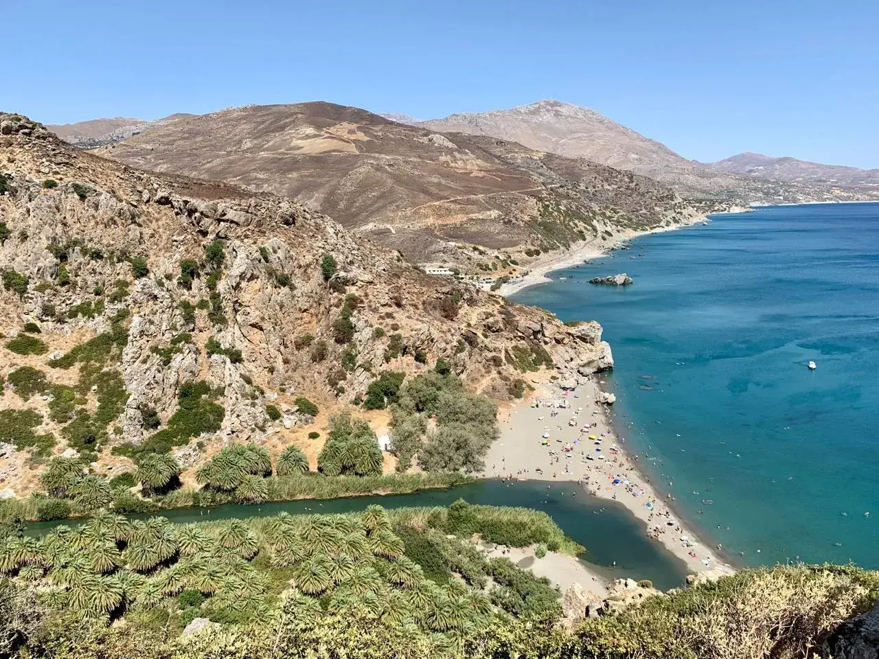 Rajska plaża na Krecie, idealna na wpis na kreta blog. Woda, góry i palmy tworzą niezapomniany widok.