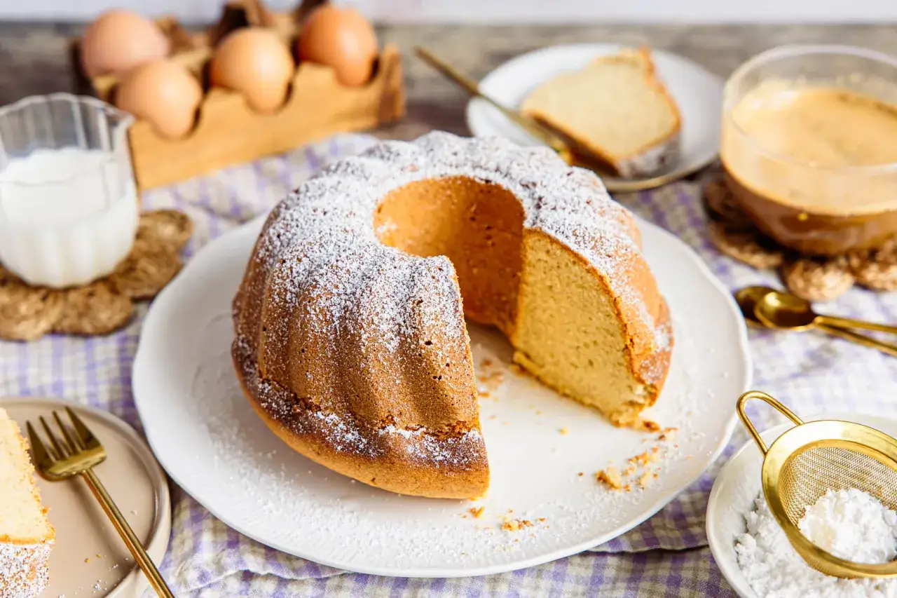 Ein saftiger Kuchen mit Puderzucker, serviert mit Apfelmus, Milch und Kaffee.