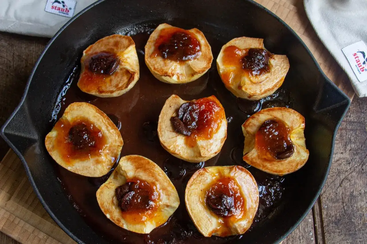 Pommes au four recette : des quartiers de pommes dor&eacute;s, garnis d'une compot&eacute;e de fruits et cuits dans une po&ecirc;le en fonte.