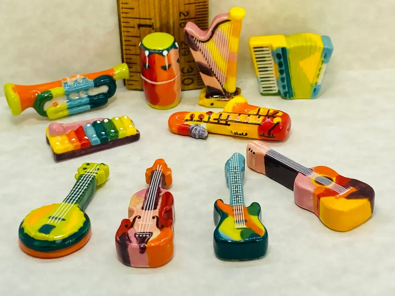 Kolekcja kolorowych, małych instrument&oacute;w muzycznych: trąbka, bębenek, harfa, akordeon, ksylofon, saksofon, gitary i skrzypce.