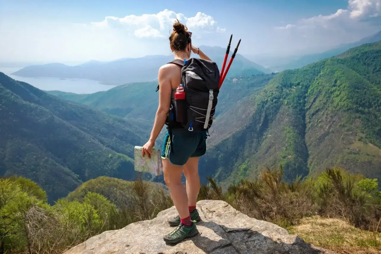 Kobieta z plecakiem i mapą podziwia widok podczas **trekking a hiking** w g&oacute;rach.
