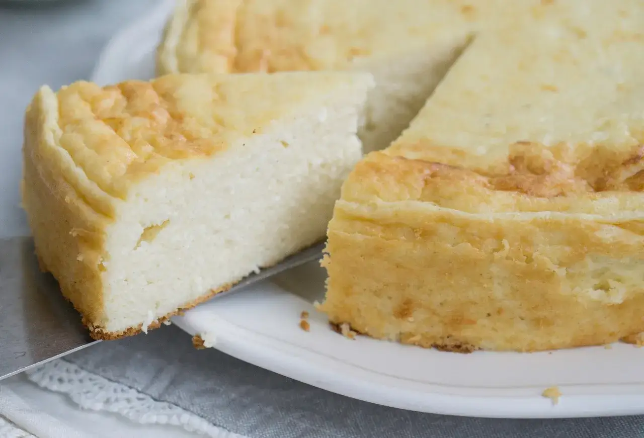 Puszysty sernik z mascarpone, z lekko zarumienioną skórką, kroimy na talerzu.